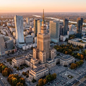 Słoneczna alejka w Łazienkach Królewskich w Warszawie z widokiem na historyczną architekturę otoczoną wrześniową zielenią